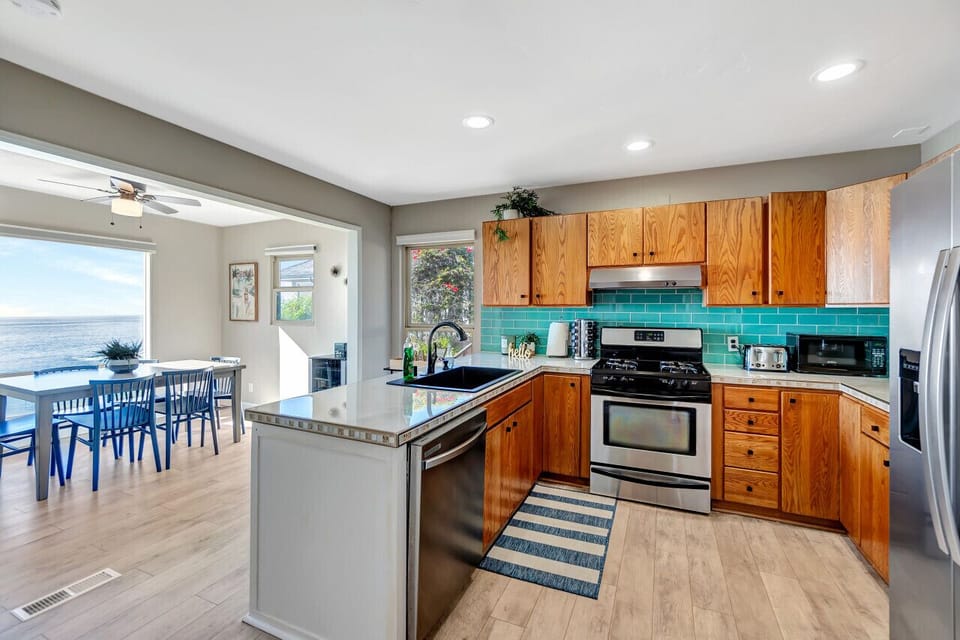 Spacious kitchen w/ turquoise tile backsplash & open flow to the dining area.