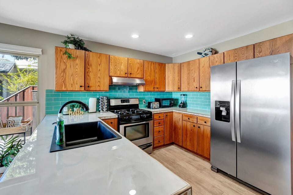 Spacious kitchen layout w/ stainless steel fridge & bar seating.