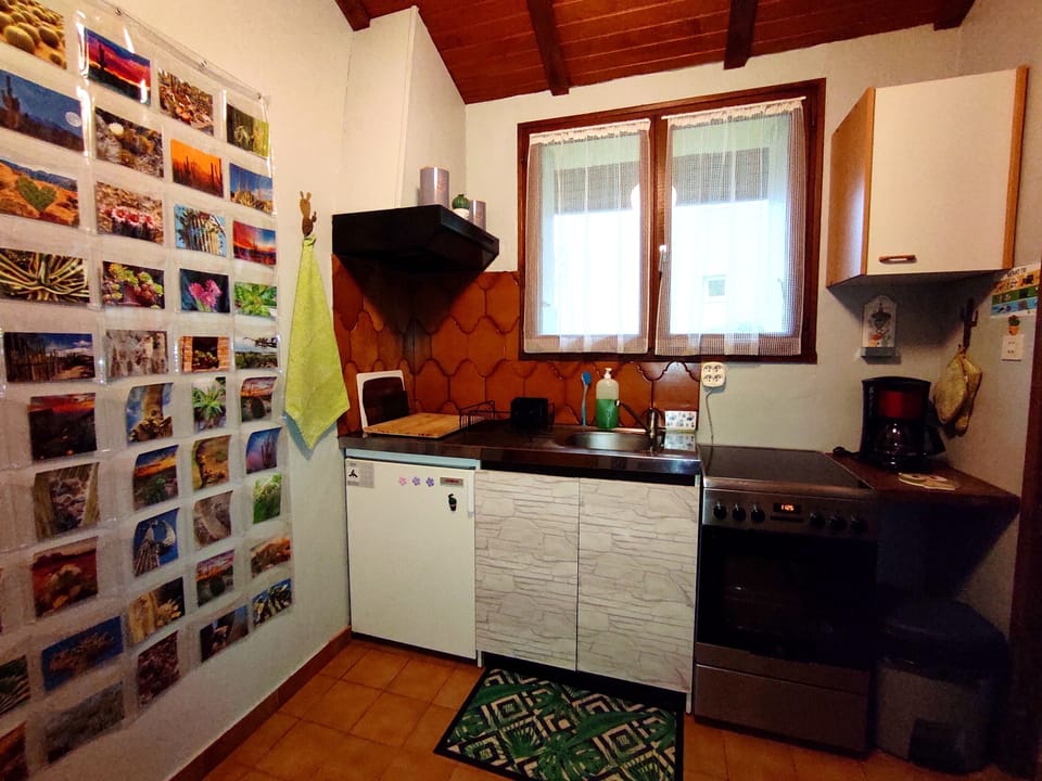 Cuisine avec cuisinière plaques vitrocéramique, frigo et cafetière.