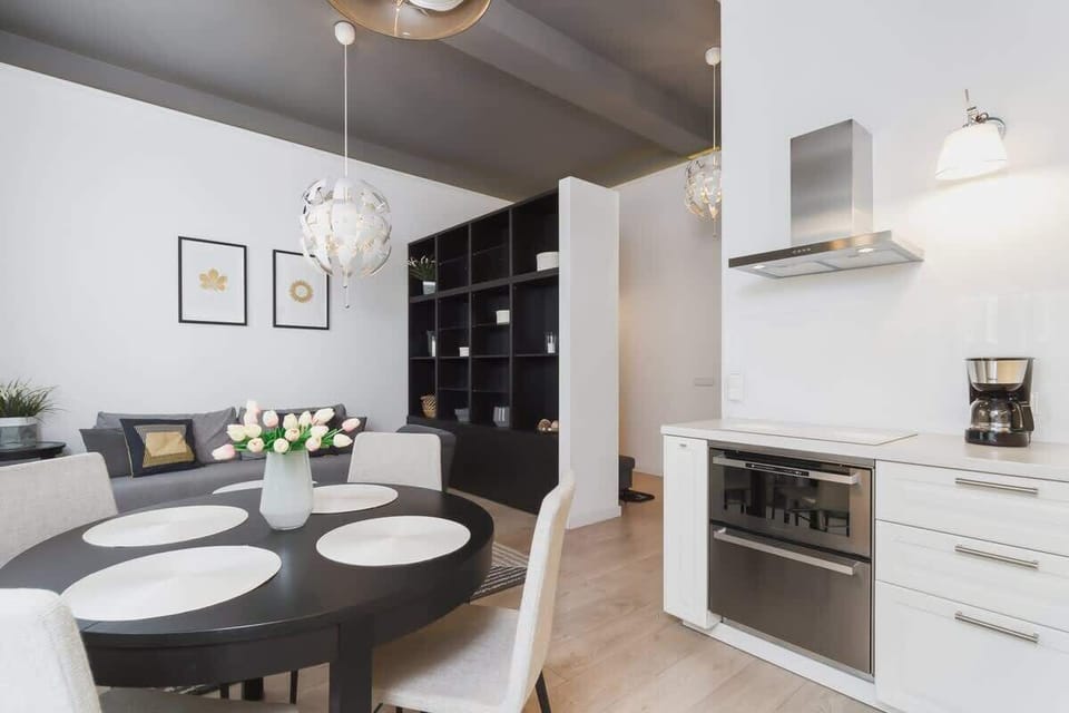A full view of a kitchen setup with modern white cabinets, an oven, and various kitchen appliances. The space is organized and well-lit.