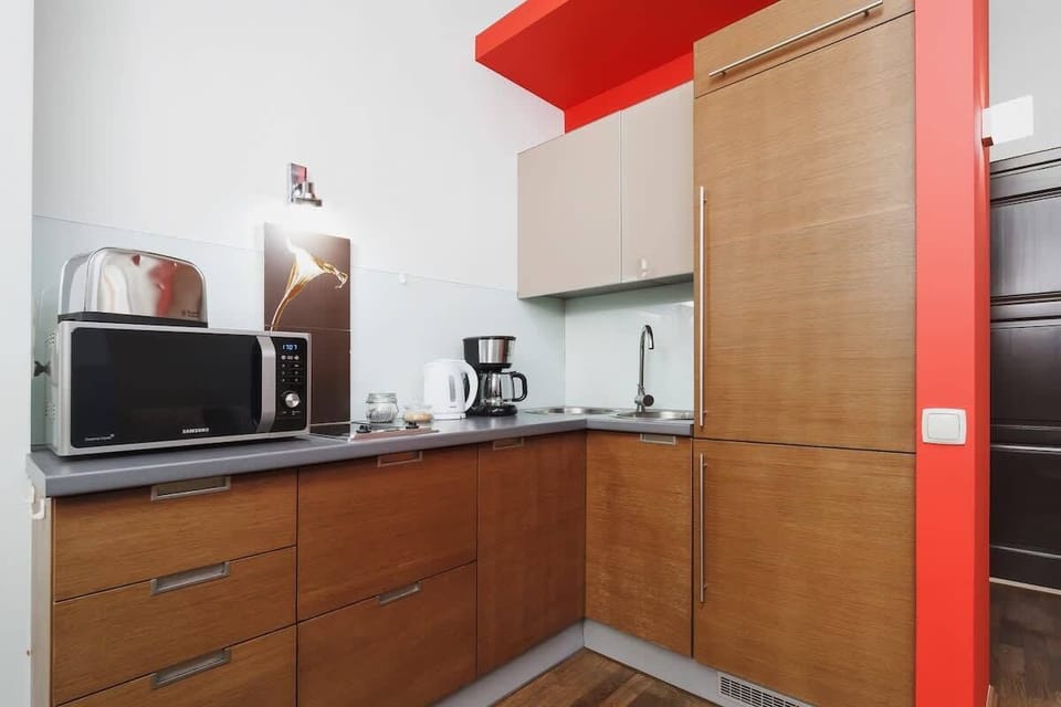A well-equipped kitchen featuring a microwave, coffee maker, and ample counter space, with striking red and wooden accents adding warmth to the space.
