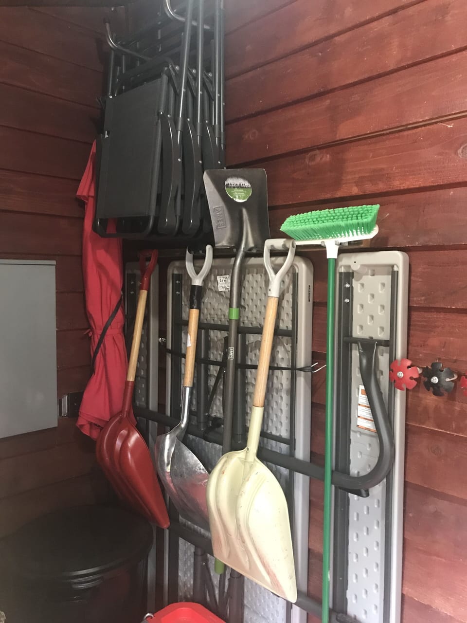 Mud room with picnic table, umbrella, chairs, shovels and broom.
