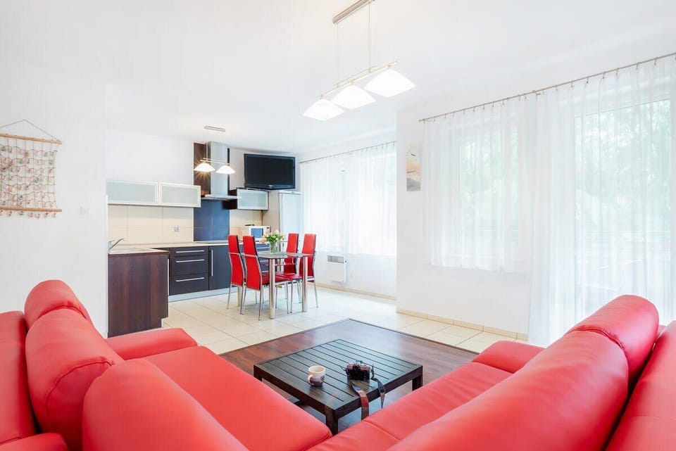 The living room features a red sectional sofa and a dining table with chairs. The space feels modern and comfortable.