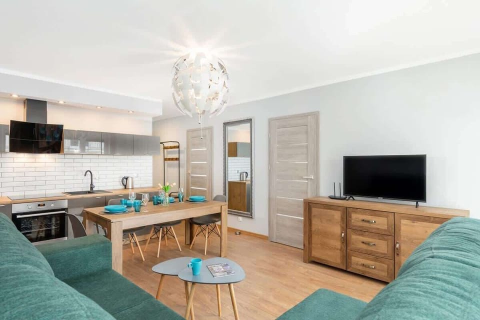 Living room with a cable TV, fold-out sofa bed, dining area with a kitchenette.