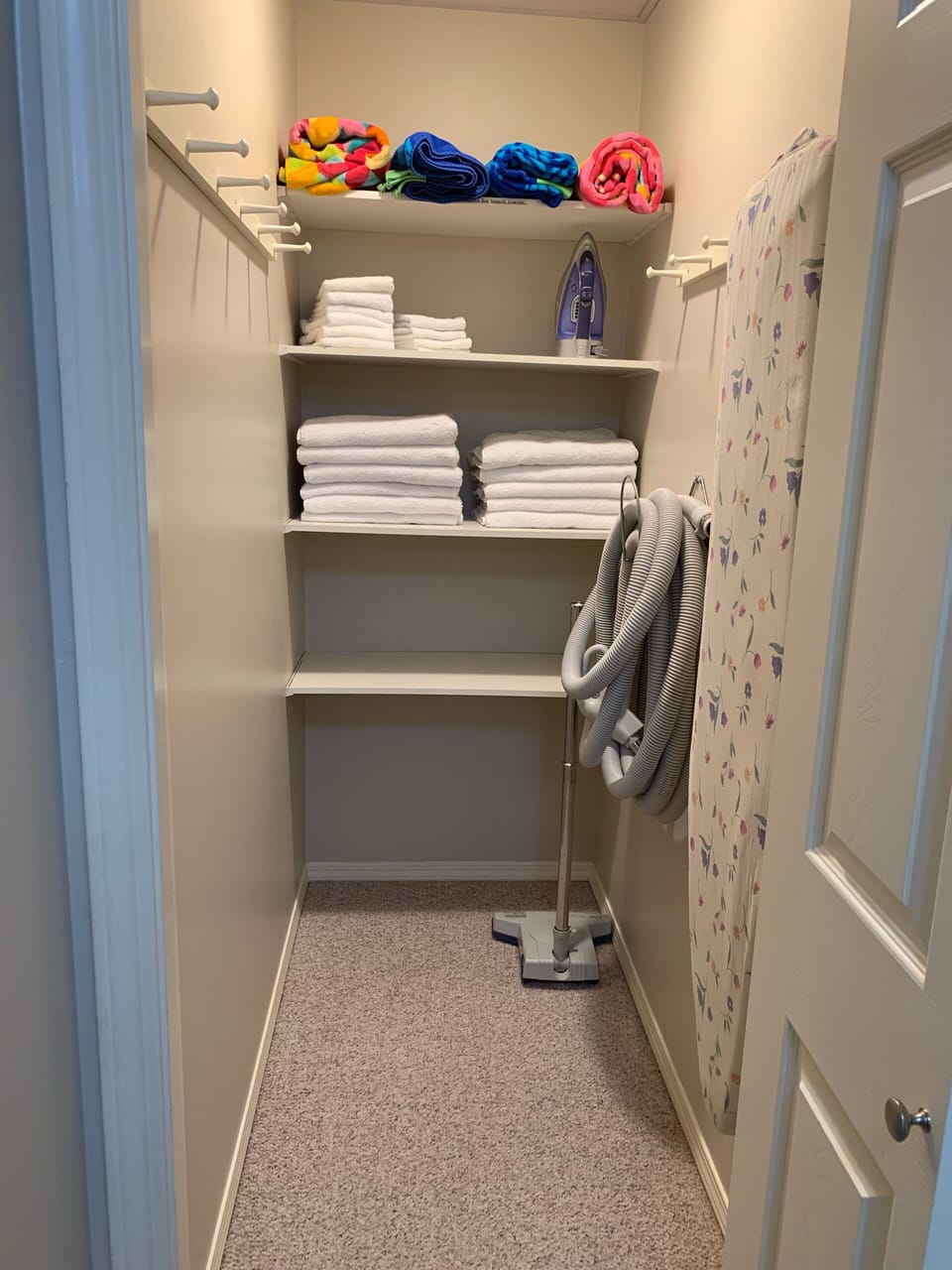 Linen closet with towels, iron and ironing board. 