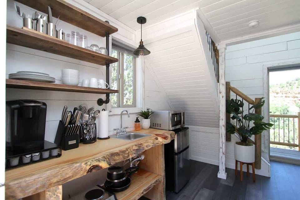 Treetop kitchenette with kitchenware, utensils, hot plate, microwave, mini fridge, and coffee essentials for easy meals and snacks during your stay.