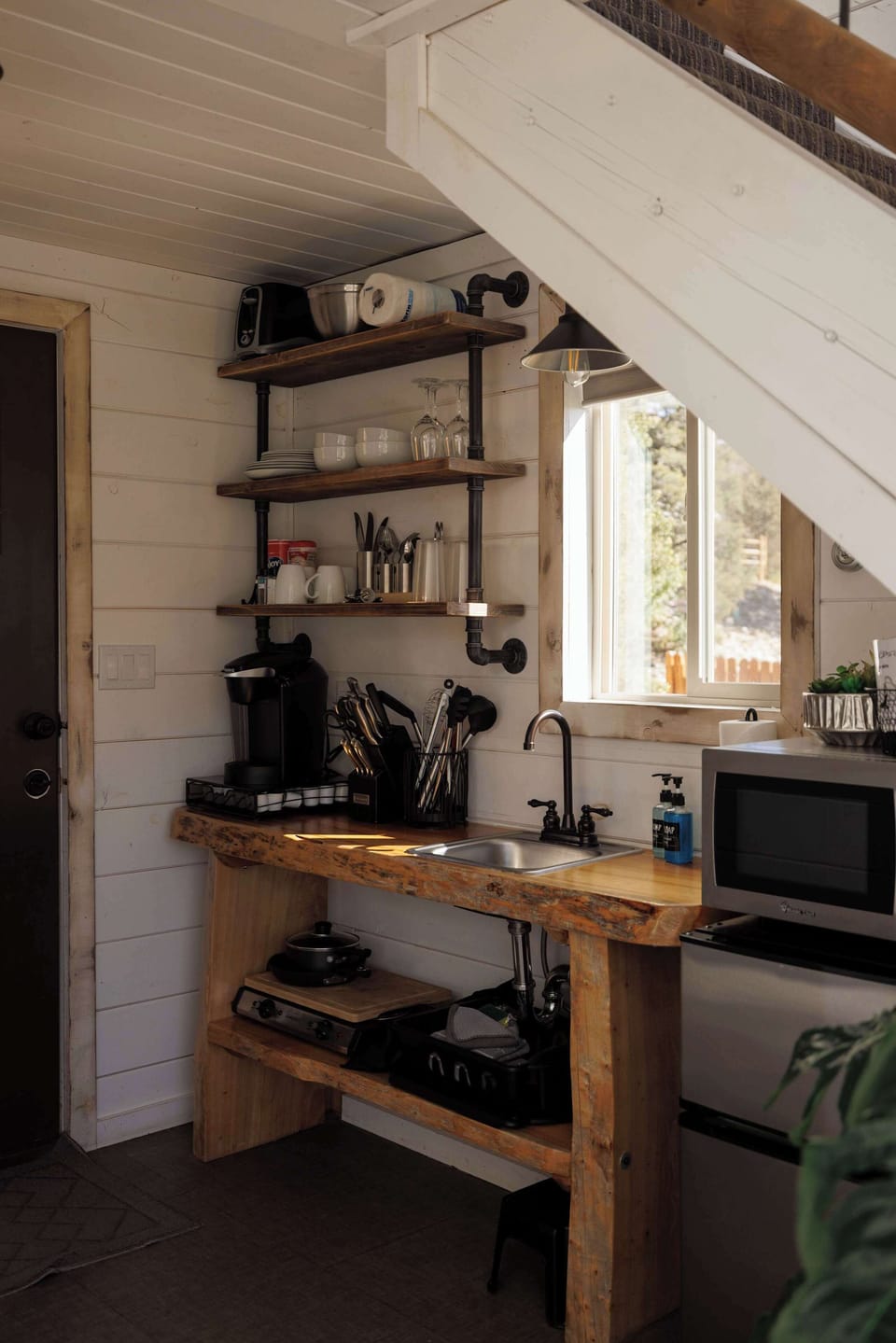 Treetop kitchenette with kitchenware, utensils, hot plate, microwave, mini fridge, and coffee essentials for easy meals and snacks during your stay.