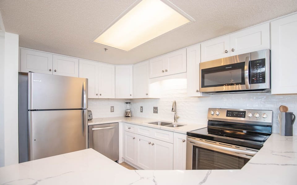 Modern kitchen featuring white cabinetry, sleek countertops, and stainless appliances, perfect for meal preparation