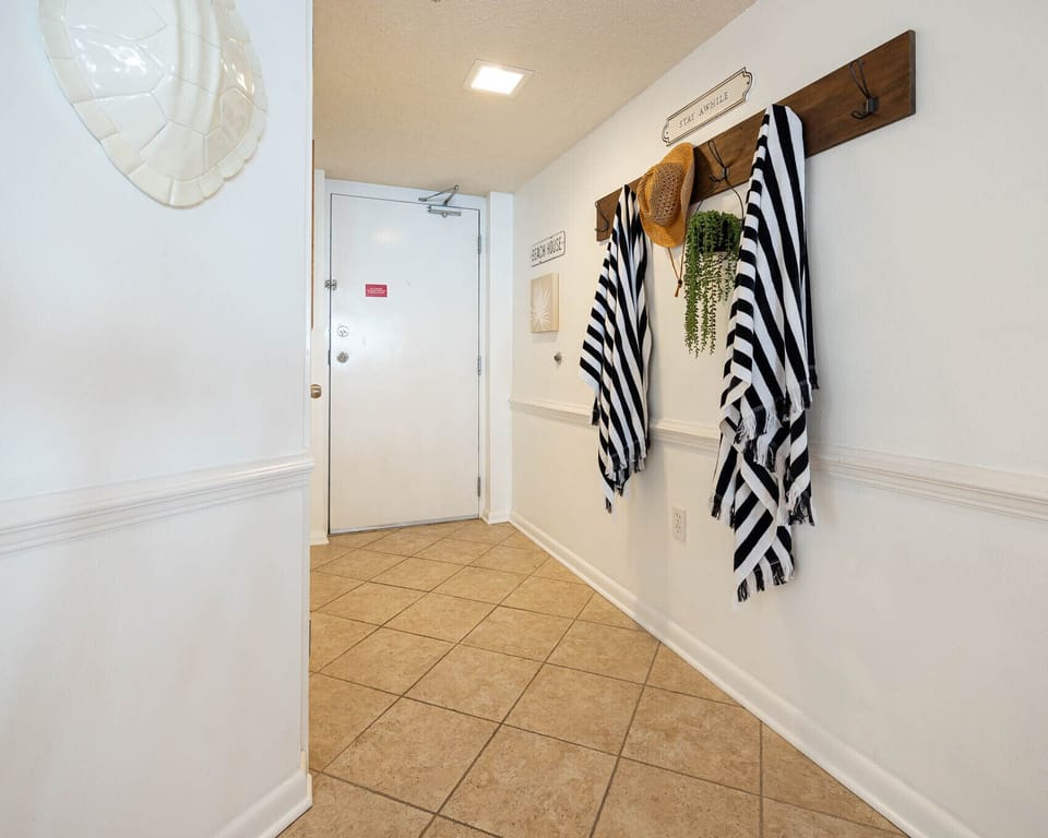 Entryway featuring a welcoming design with striped towels, a straw hat, and decorative wall art, setting a beachy vibe