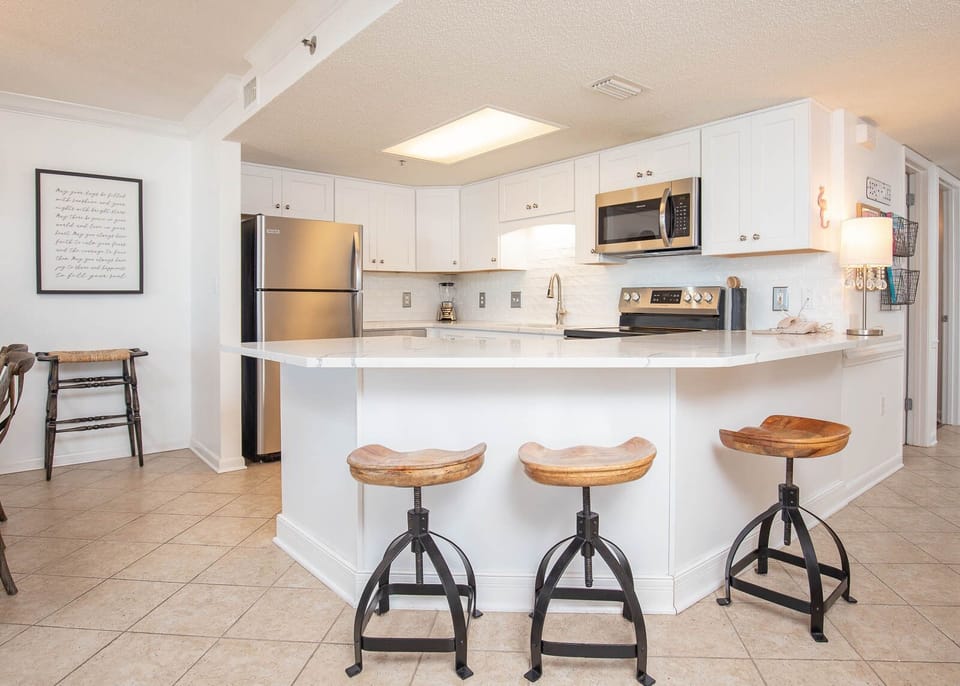 Bright kitchen area featuring white cabinetry, granite countertops, and stylish bar stools at the breakfast bar