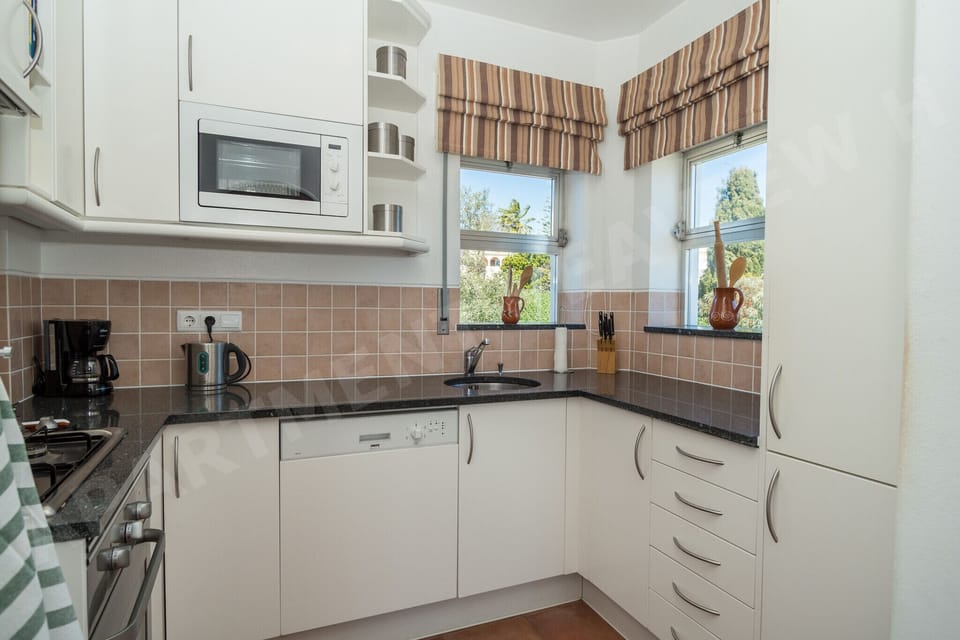 Fully equipped kitchen in Seaview Apartment H with tiled backsplash, white cabinets, oven, and hob for self-catering holidays in Praia da Luz