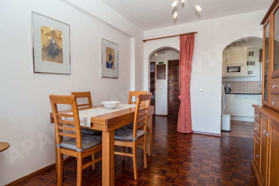 Spacious dining area with wooden table and chairs, artwork on the walls, and plenty of natural light in Seaview Apartment H, Praia da Luz