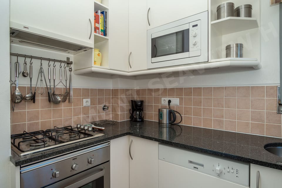 Well-equipped kitchen with hanging utensils, fridge, and modern appliances for self-catering in Seaview Apartment H, Praia da Luz on the Algarve coast