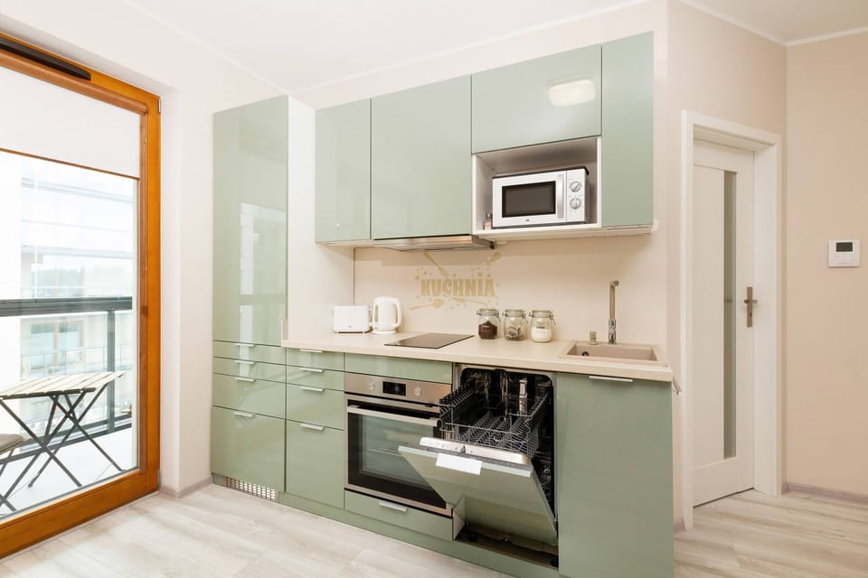 Kitchenette with an induction hob, microwave, oven, kettle, fridge freezer, dishwasher, coffee maker, toaster and access to the balcony.