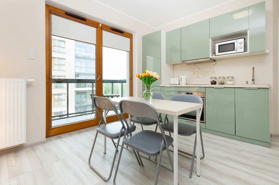 Fully equipped kitchenette with induction cooktop, dining area and access to the balcony.