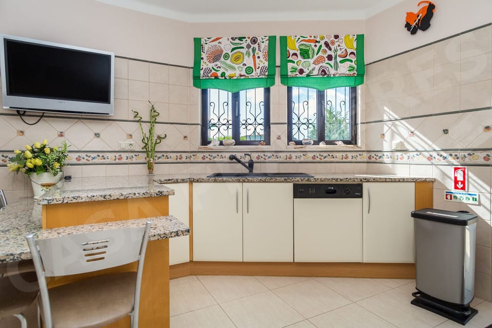 Bright kitchen and breakfast area at Casa Prazeres holiday villa in Carvoeiro, Algarve, featuring traditional Portuguese azulejo tile work, TV, and a welcoming atmosphere for family meals