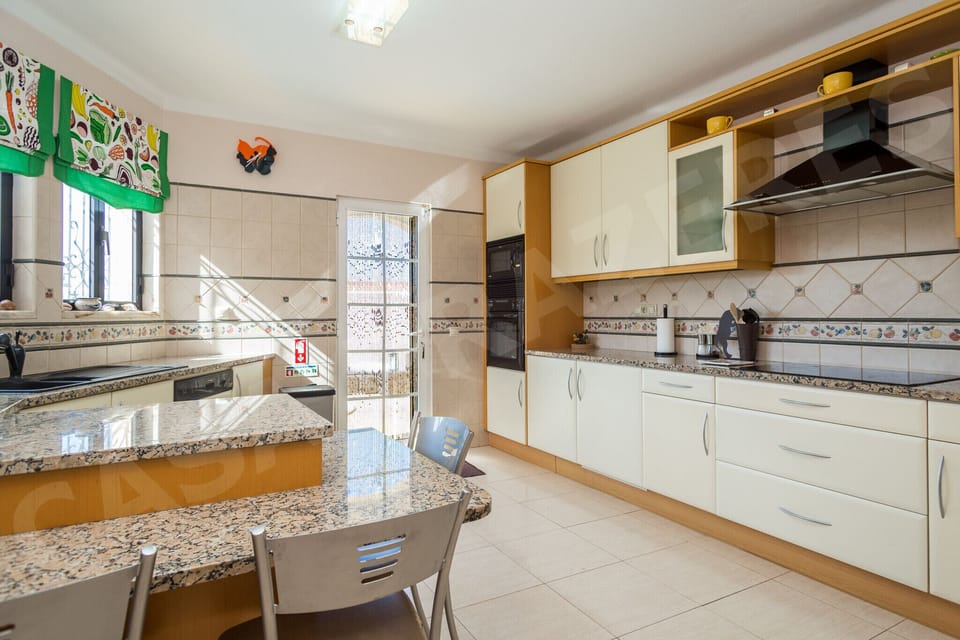 Traditional Portuguese-style kitchen at Casa Prazeres villa in Carvoeiro, Algarve, featuring decorative azulejo tiles, dining area, and natural light for a charming self-catering experience