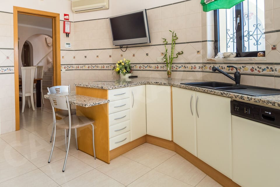 Kitchen utility area and workspace at Casa Prazeres holiday villa in Carvoeiro, Algarve, with additional counter space, desk area, and access to the garden through patio doors