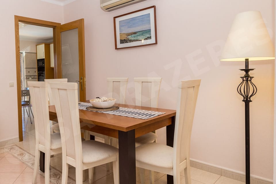 Bright dining room at Casa Prazeres with wooden table seating six and views to the garden, near Carvoeiro.
