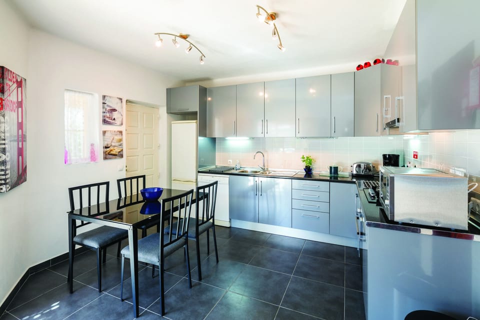Fully equipped modern kitchen with dining area featuring a glass-top table and comfortable seating at Casa Santalena villa in Carvoeiro, Algarve