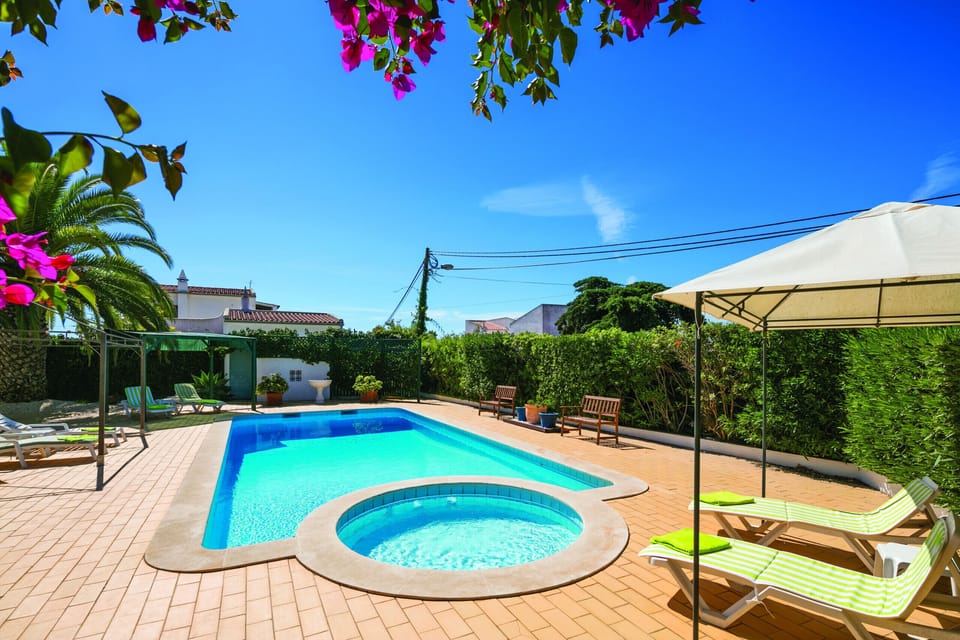 Swimming pool and jacuzzi surrounded by flowering bougainvillea and mature gardens at Casa Santalena villa in Carvoeiro, Algarve