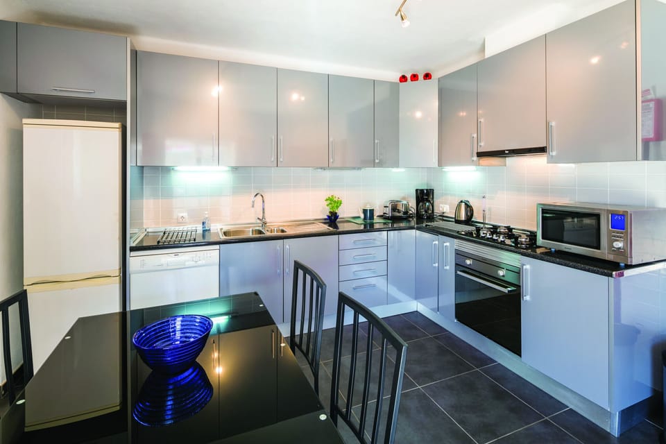 Modern kitchen with dark granite countertops, under-cabinet lighting, and stainless steel appliances at Casa Santalena villa in Carvoeiro, Algarve