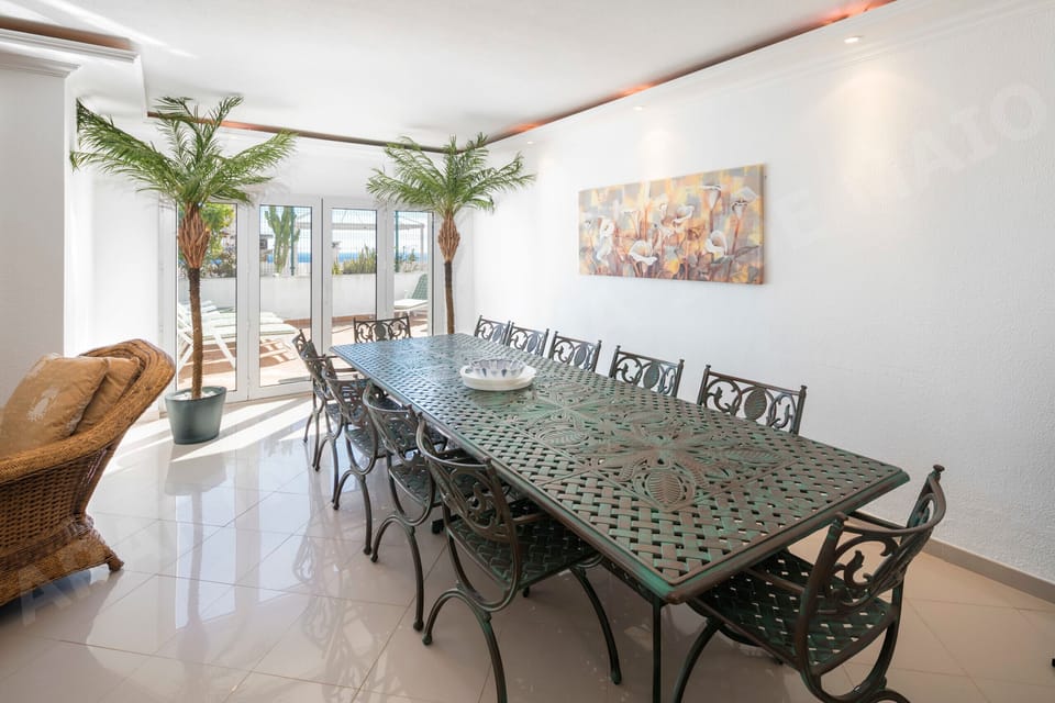 Bright dining area with balcony access and indoor plants at Rua 1º de Maio apartment in Praia da Luz, offering a welcoming space for family meals during your Algarve holiday
