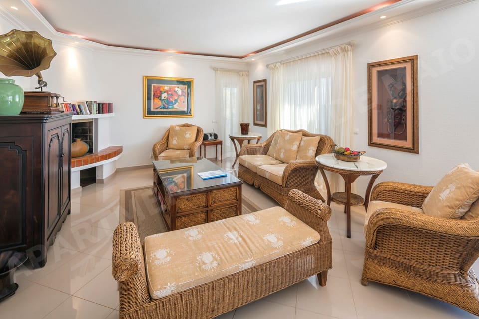 Cosy living room in Rua 1º de Maio apartment, Praia da Luz, with comfortable wicker armchairs, warm lighting, and traditional Algarve decor creating a welcoming atmosphere for holiday guests