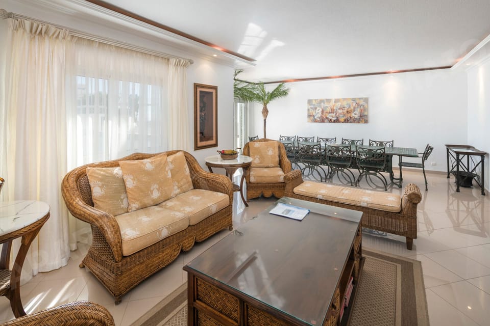 Comfortable living room with rattan furniture and indoor plants at Rua 1º de Maio apartment in Praia da Luz, a relaxing space for unwinding during your Algarve holiday
