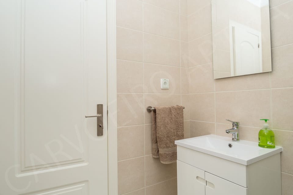 Modern bathroom with walk-in glass shower and towel rail in this professionally cleaned holiday apartment near Carvoeiro, Algarve