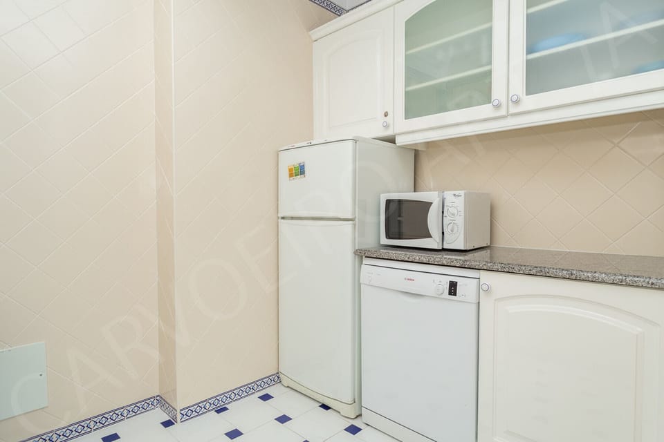 Fully equipped kitchen with modern appliances and tiled flooring in this holiday apartment near Carvoeiro, Algarve