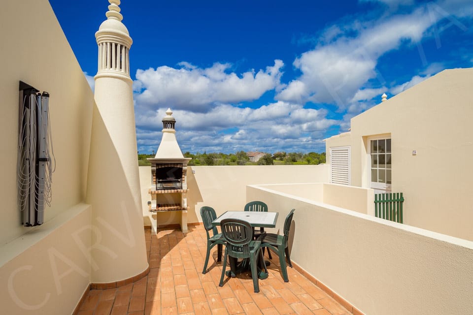 Sunny terrace with patio furniture and parasol offering al fresco dining at Carvoeiro Apartment 7A, Algarve