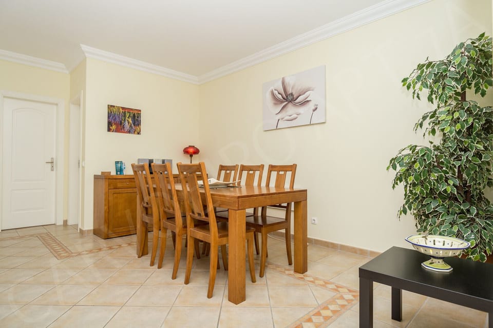 Bright dining area in Carvoeiro Apartment 7A featuring a solid wooden dining table with seating for six, perfect for family meals in this comfortable Algarve holiday rental