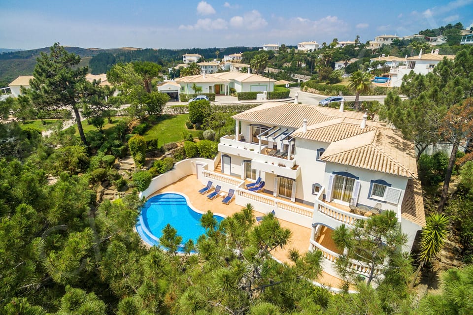 Aerial view of Casa Clajon 4-bedroom villa showing the private pool, sun terraces, and lush Algarve landscape on a golf course near Carvoeiro with countryside and sea views