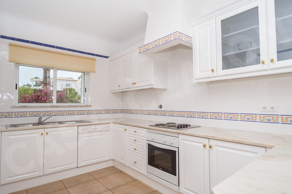 Fully equipped kitchen at Casa Clajon holiday villa near Carvoeiro, Algarve, with white cabinetry, built-in oven, and ample worktop space for preparing meals. The kitchen includes all essential appliances and utensils needed for a comfortable self-catering holiday in the Algarve.
