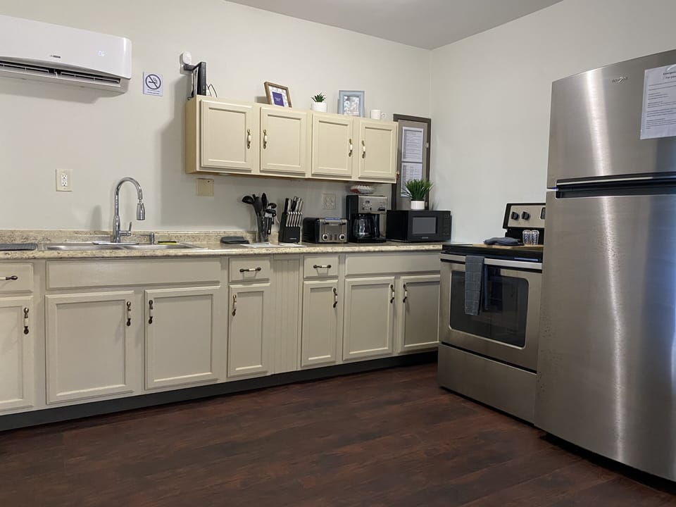 Kitchen with stove, refrigerator, coffee maker, microwave and utensils.