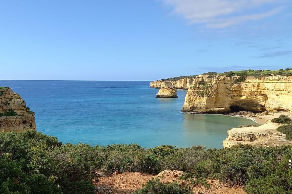 Spectacular Algarve coastline with golden limestone cliffs and crystal-clear turquoise waters near Alvor, a short drive from Vila Golfemar holiday apartment