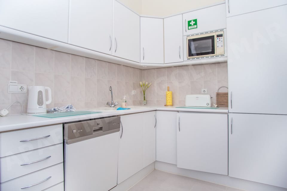 Well-equipped kitchen in Vila Golfemar apartment with clean white cabinets, microwave, and modern appliances, providing everything needed for self-catering during your Algarve holiday