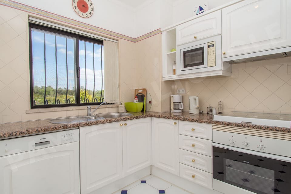 Fully equipped kitchen at Apartment Pampas with white marble countertops, modern appliances, and a window letting in natural light, everything you need for self-catering holidays near Alvor