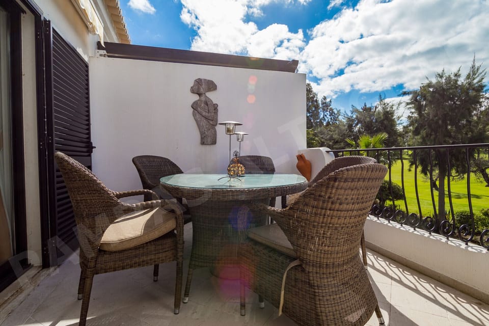 Private balcony at Apartment Pampas with rattan chairs and a small table, perfect for morning coffee or evening drinks while enjoying views of the gardens and golf course near Alvor