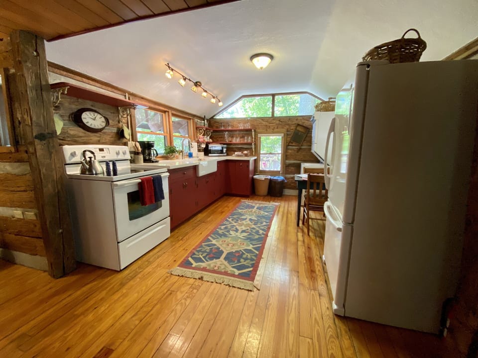Kitchen with cookware, dishes, glasses, utensils, microwave, coffee & tea pots.