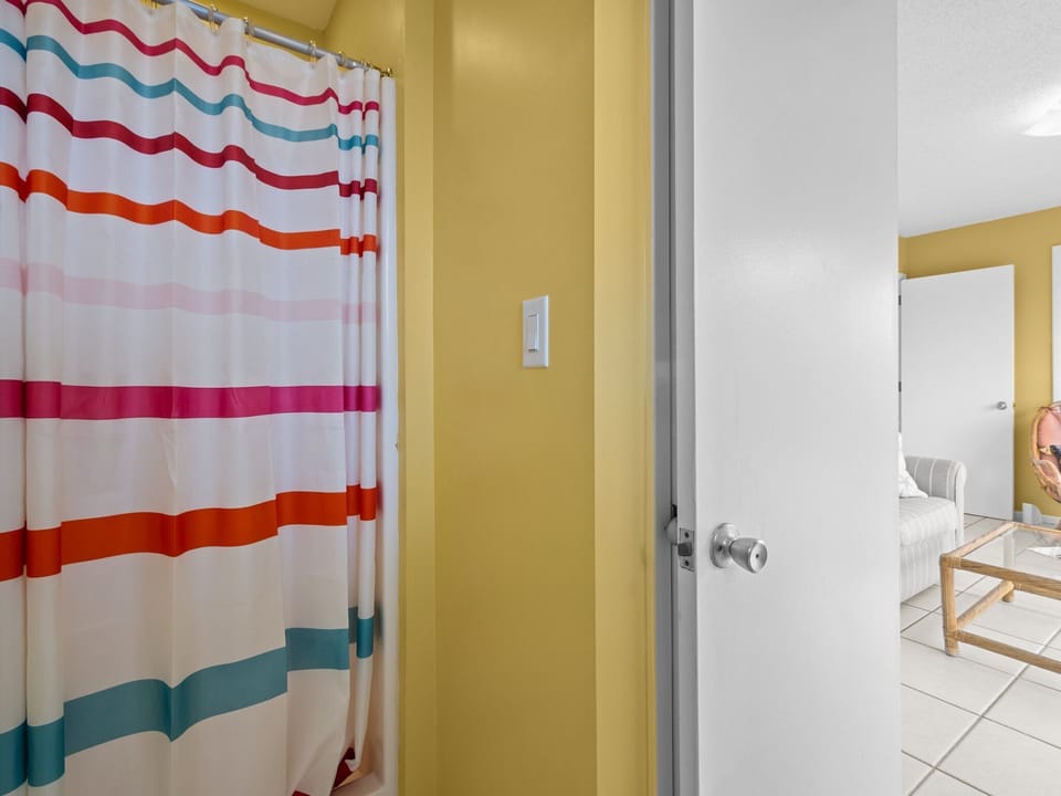 Refresh in your vibrant bathroom featuring colorful striped shower curtains and cheerful yellow walls that brighten your morning routine.