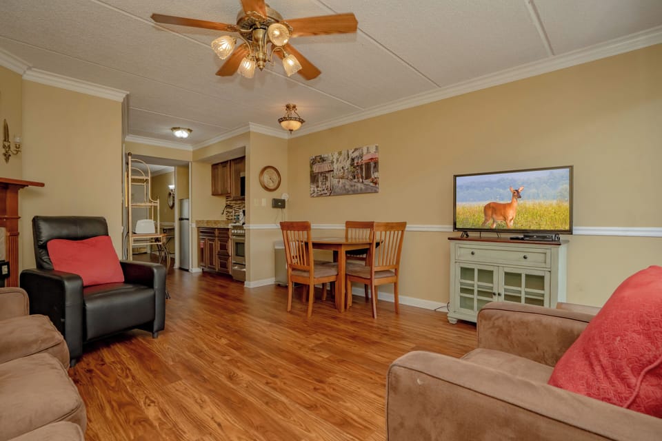 Cozy open-plan living and dining area with warm wood floors and comfortable seating. The dining table and nearby kitchen make this the perfect space for gathering and entertaining.