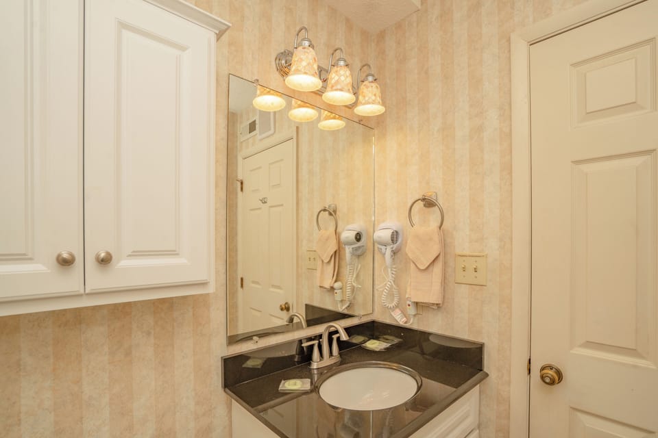 Your private bathroom features warm lighting, a polished granite vanity, and thoughtful touches like mounted hair dryers—everything you need to refresh and get ready comfortably.