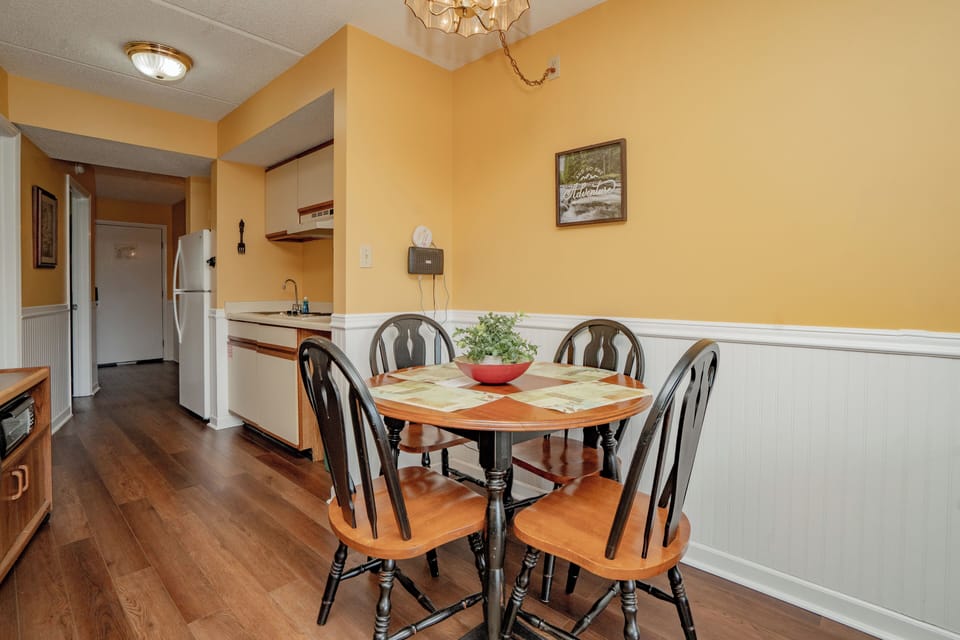 Gather around this welcoming dining table in your cozy kitchen space, warmed by golden walls and natural light—perfect for morning coffee or sharing meals with loved ones.