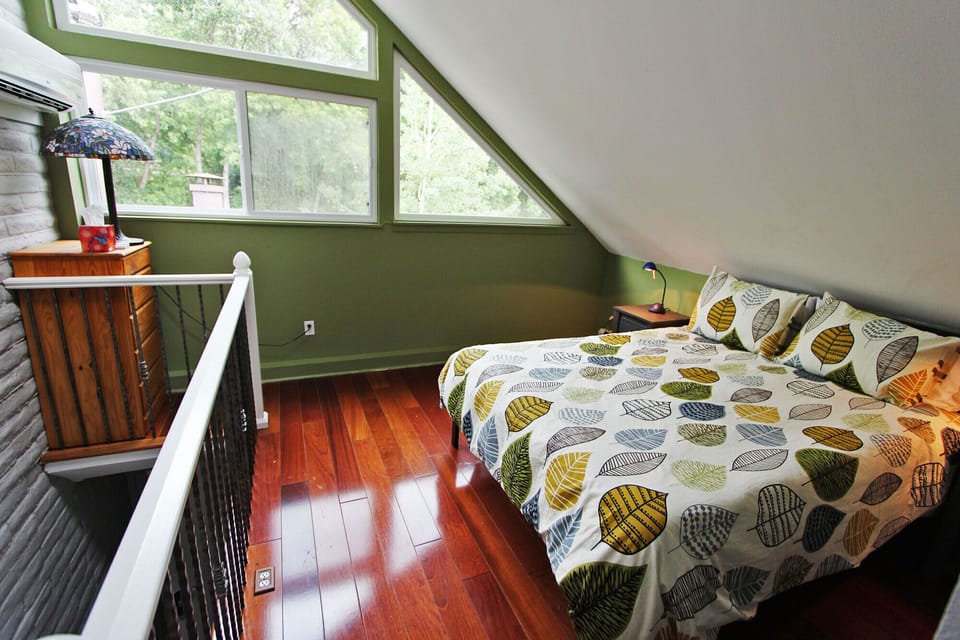 Loft bedroom with queen bed, closet, and large windows (no TV)