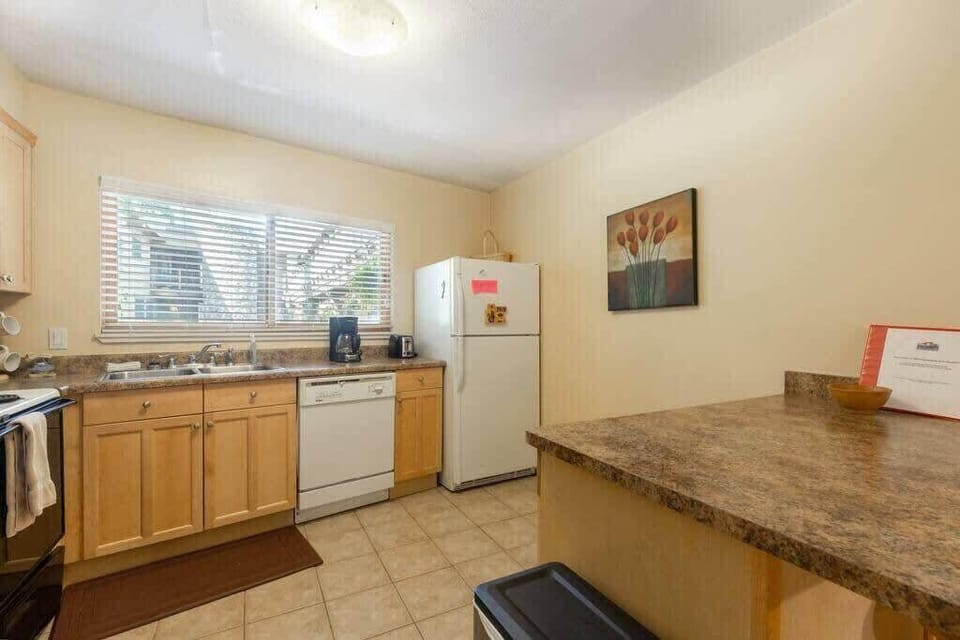 The charming kitchen is fully equipped with everything you need to whip up a meal, including a bar/island with seating for two, ample cabinet and counter space and natural light thanks to the over-the-window sink.