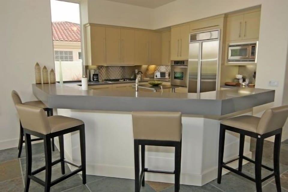 Fully equipped oversized kitchen with stainless appliances, stainless backsplash