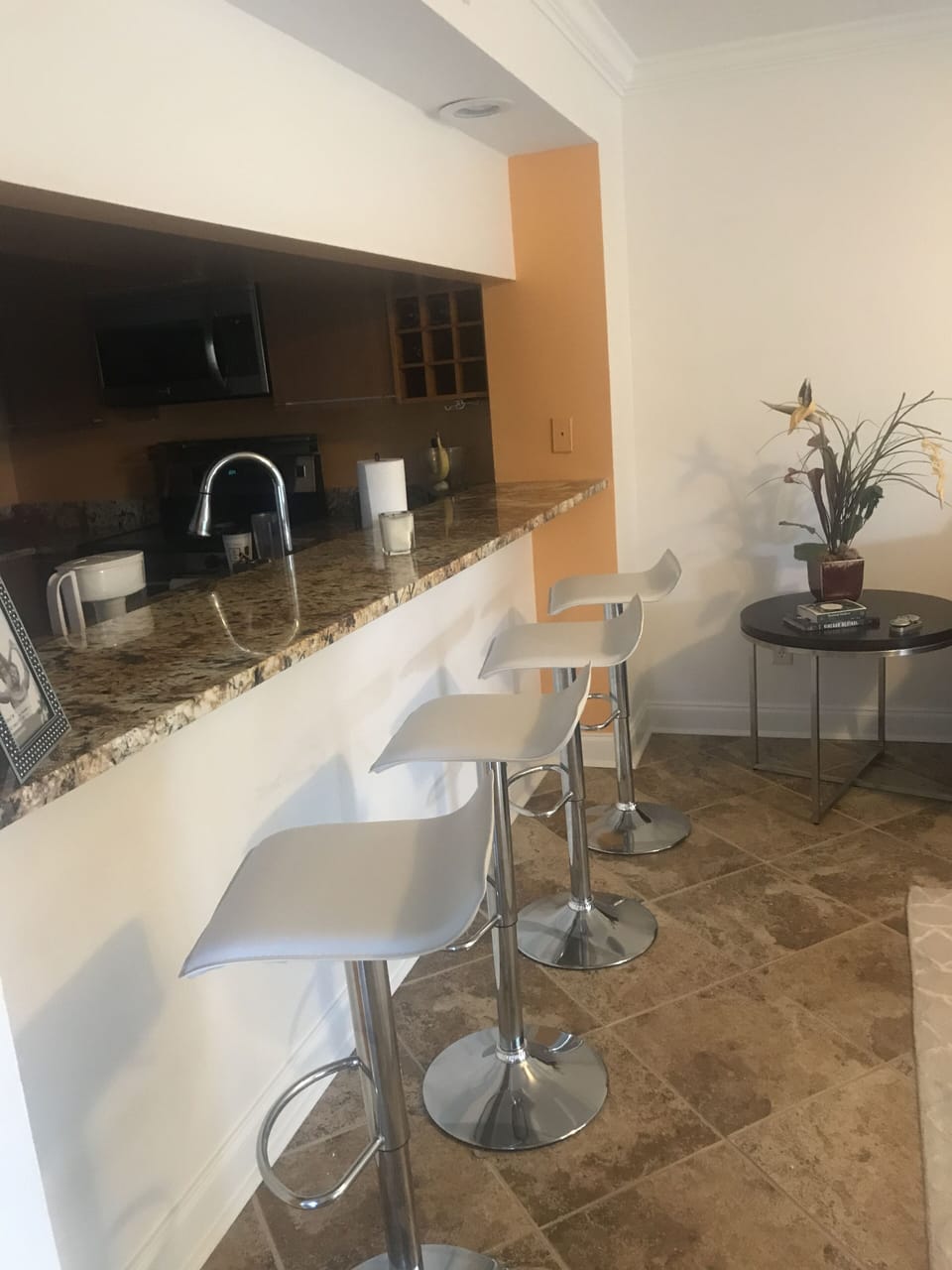 Kitchen bar area open to living room and floor to ceiling windows outside 