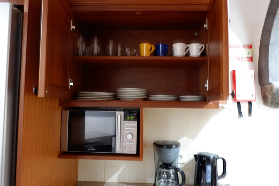 Full kitchen with dishes, microwave, kettle and coffee machine